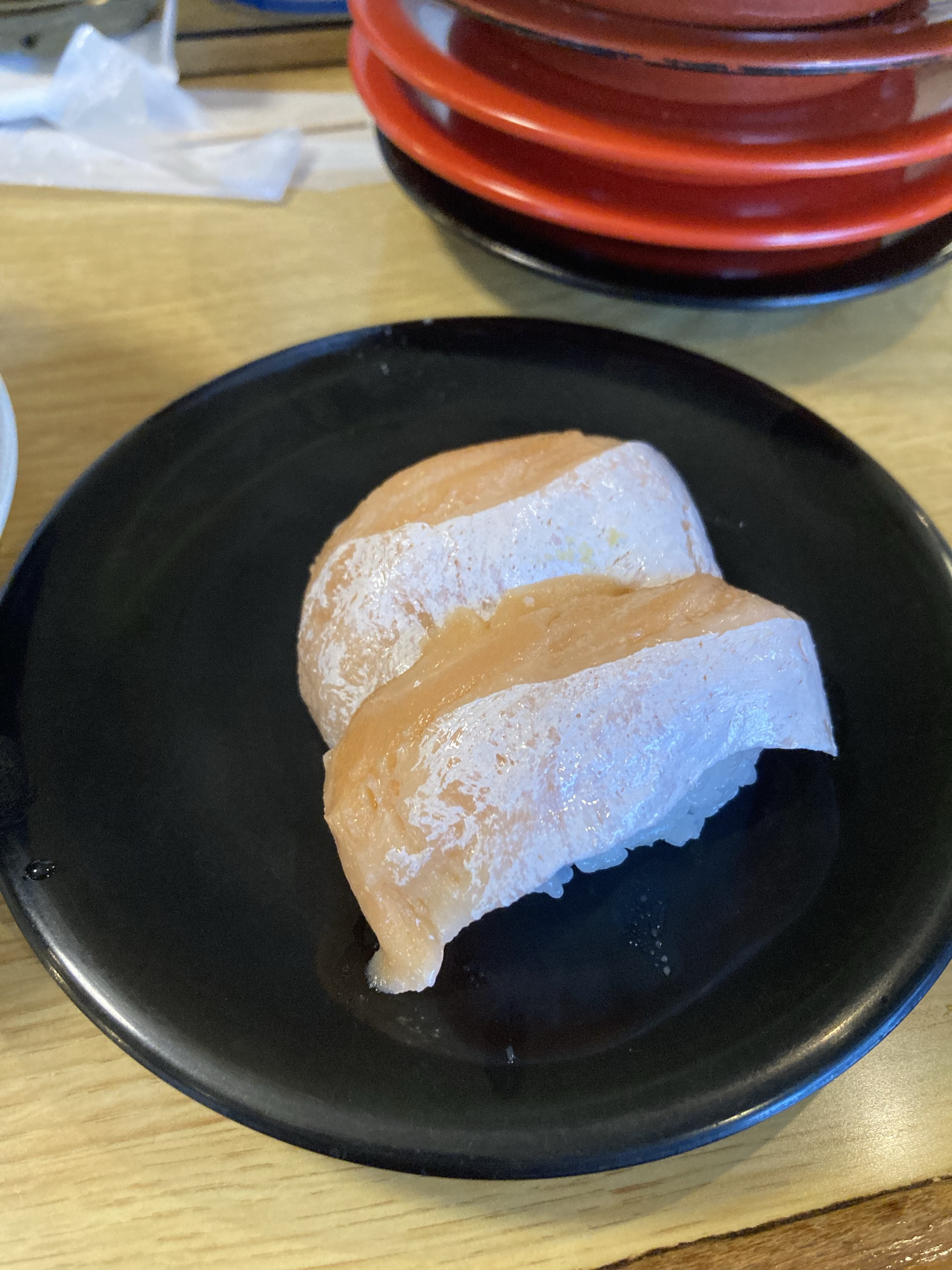 黒い皿に並んだサーモンの握り2貫