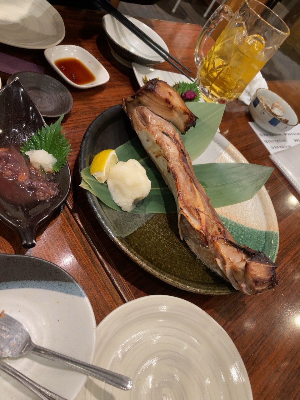 皿に盛られたまぐろのカマ焼きと、レモン、大根おろし